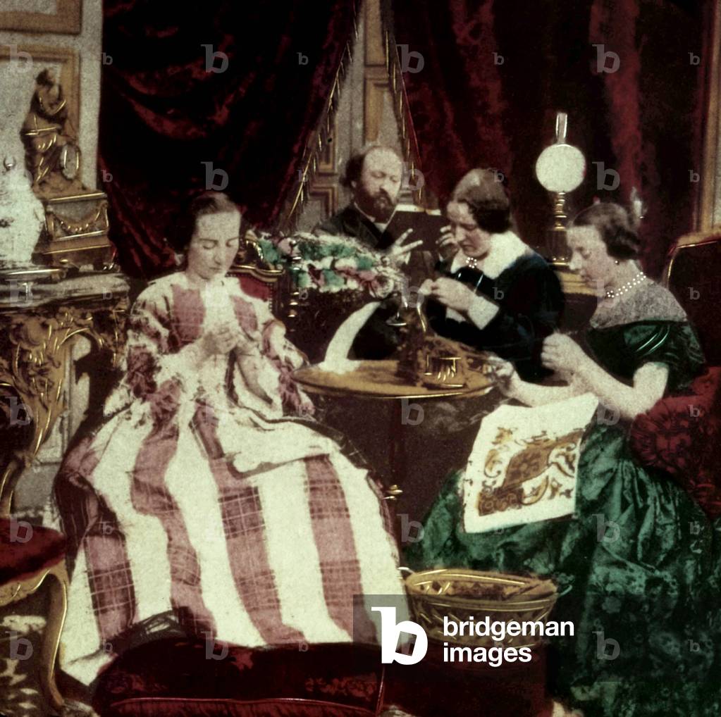 Interior scene in 2nd empire in France (1852-1870) : women, with crinolines, are sewing while man is reading
