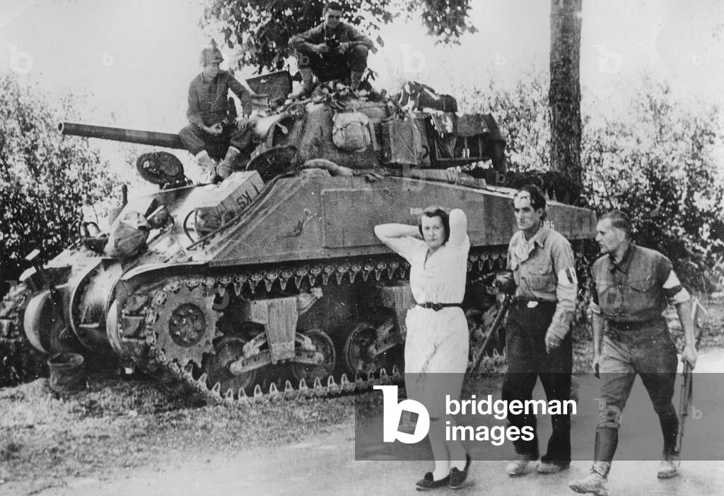 French woman accused to have collaborated with the germans during the war, here arrested by two resistants after the liberation in France late august 1944 behind them is an american tank Sherman M4-A3