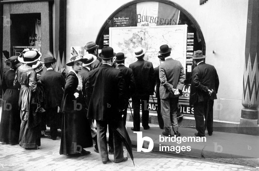 The Parisian ones observe the avancee the military troops and operations on a chart geographic affichee on a window in the streets of Paris in 1914