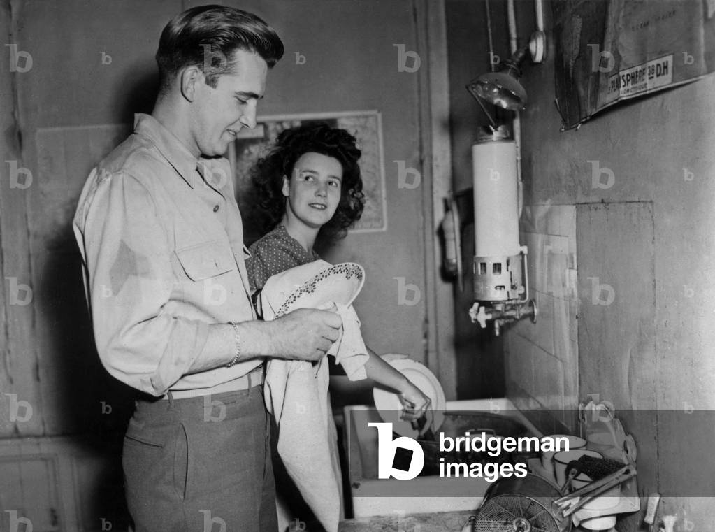 Young couple : a French woman and an american soldiers after the war c. 1946. Wa can see the interior of an appartment with a gas water-heater