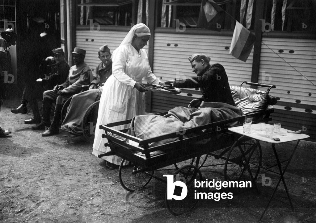Mrs Poincare (wife of the French president Raymond Poincare) opening charity for the convalescent wounded, TheophileGauthier street in Paris, on june 8, 1917. Here wearing nurse suit and offering a wounded cakes.