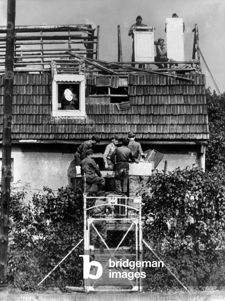The year after building of Berlin wall in 1961 : houses at border were destroyed, policemen of GDR dazzling photographers with mirrors