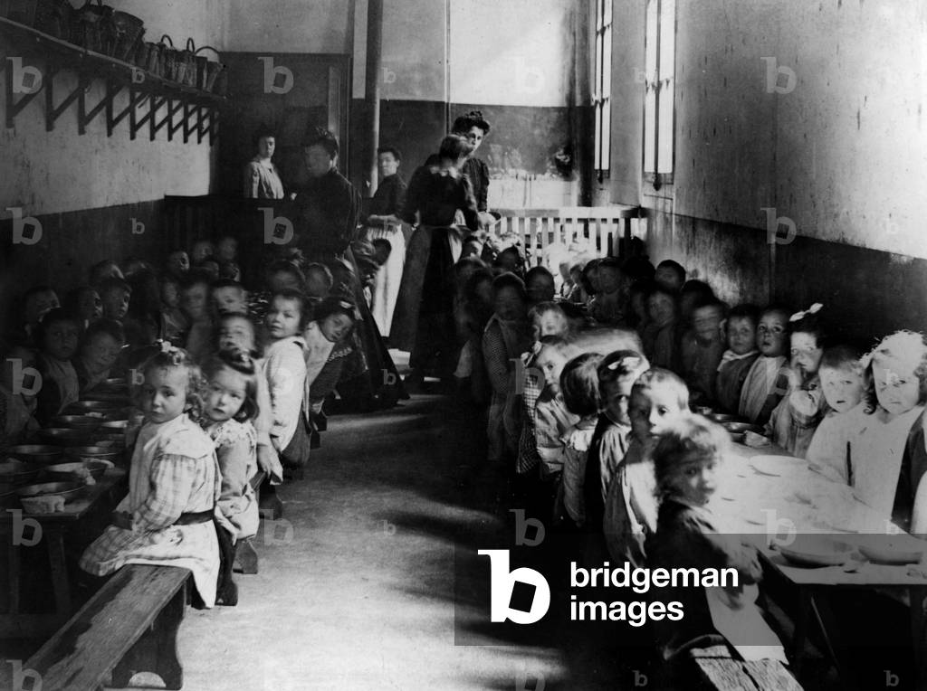 Children are eating in a school canteen in the town of Ay in Marne about 1900-1910