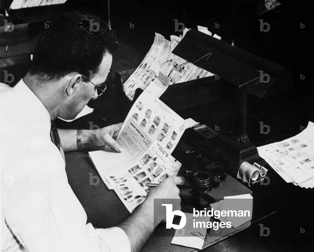 An expert comparing two fingerprints in FBI laboratory in washington, 40's