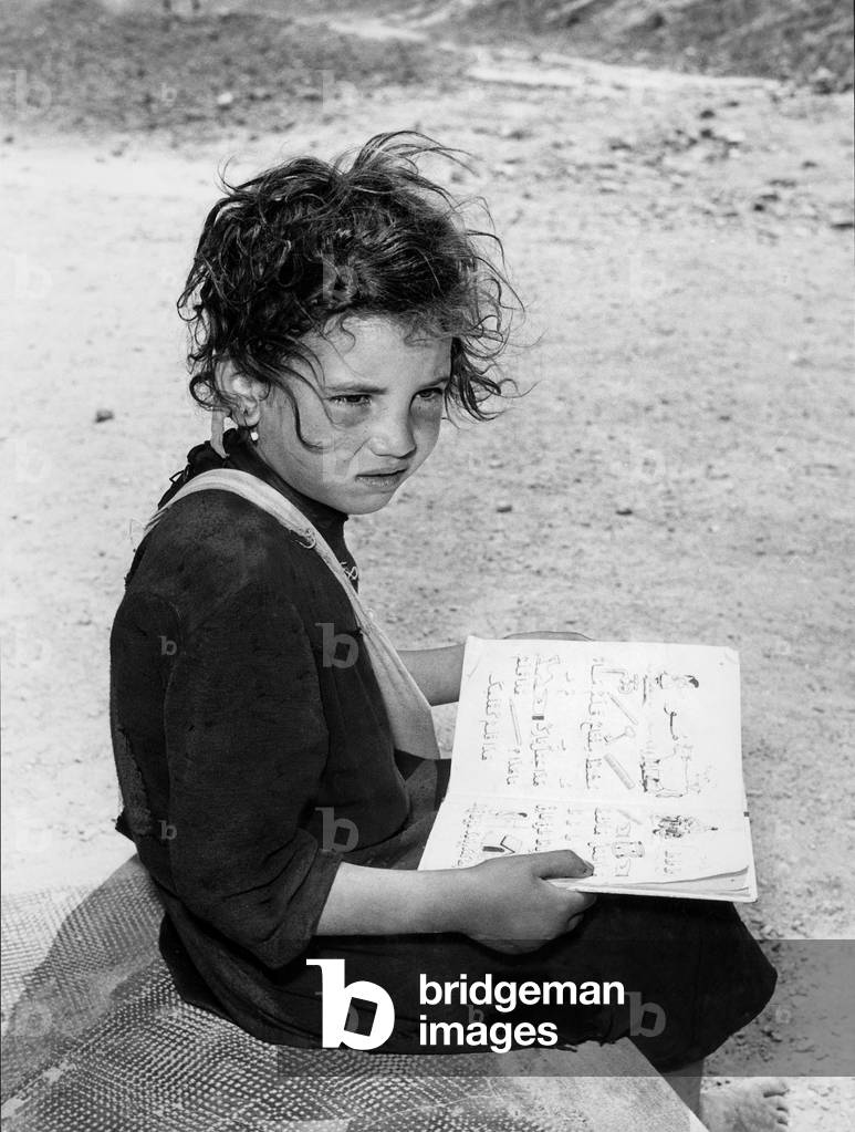 Children of Algerian soldiers who fought on the French side in the war of independence (Harkis) with her notebook in arabic, before leaving to France, 1962