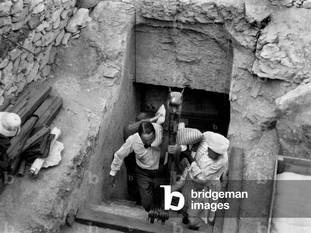 Discovery of the tomb of pharaoh Tutankhamun in the Valley of the Kings (Egypt) : Howard Carter carries with an egyptian worker's help a statue composing the treasure