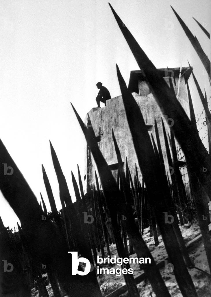Fortified village established to protect South Vietnamese peasants from communist guerilla raids are protected by fences no man's land studded with sharpeded bamboo spikes.This Vietnamese militiaman keeps watch from avantage point on the village wall c. 1960