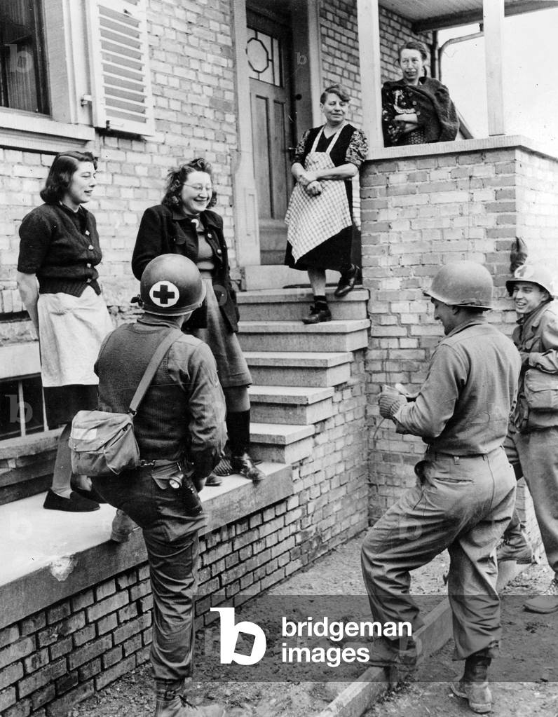 Alsatian women chat with two medicalcorpsmen and an infantryman of the 103rd Division from american U.S army in the town of Gundershoffen the 17th March 1945