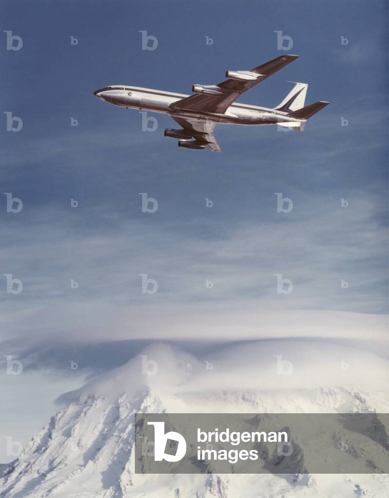 Boeing 707 flying over mountains