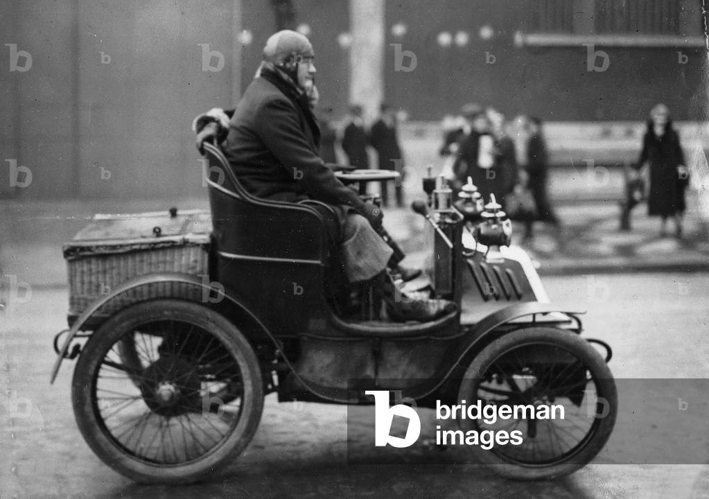 A car driven by a man with an aviator helmet and wicker basket for a trunk c. 1900