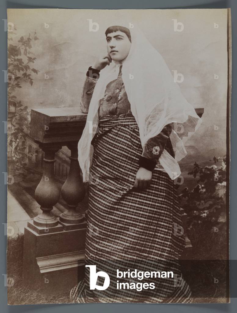 Studio shot of a woman with a white Charhad leaning against a wooden balustrade in western costume (silver albumen photo)