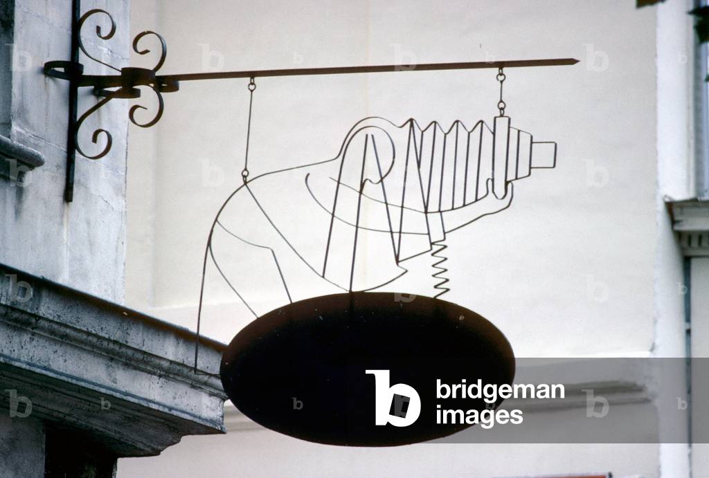 Photographer silhouette leans on the photographic chamber, made of wire, trade sign in Paris.