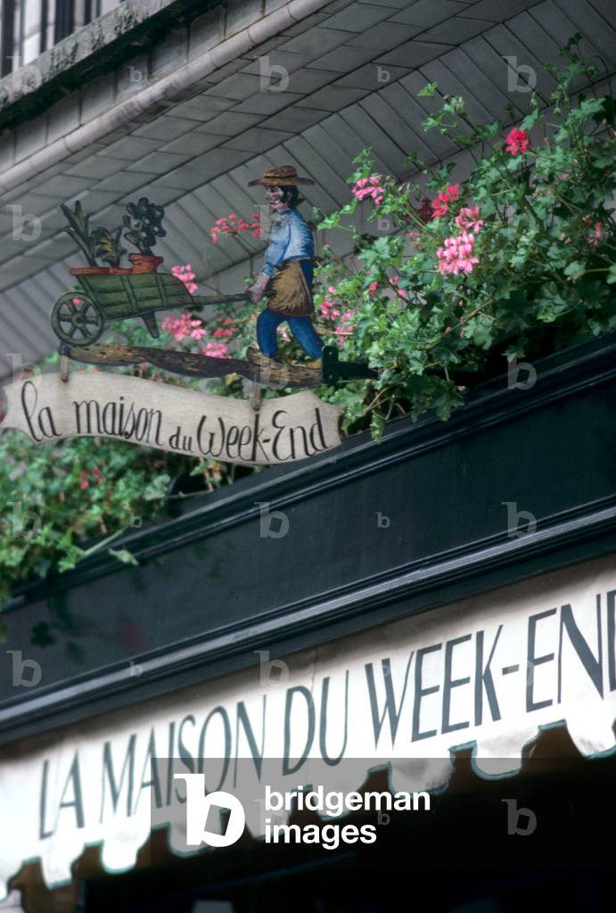 Gardener pushing his wheelbarrow full of plants, for the weekend house, trade sign in Paris.