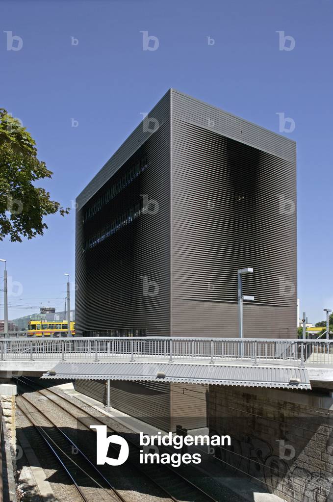 The central switch point of the Swiss railway company in Bale, Switzerland. Architects Pierre De Meuron and Jacques Herzog, construction 1998-1999. Located behind the Munchenstein Bridge, like a giant monolith, this impressive building stands above the railways. For many, this specialised industrial construction is an architectural impertinence. This cube is coated with copper with a red gold tone whose reflections change according to the lighting and angle of view. Photography 10/06/05.