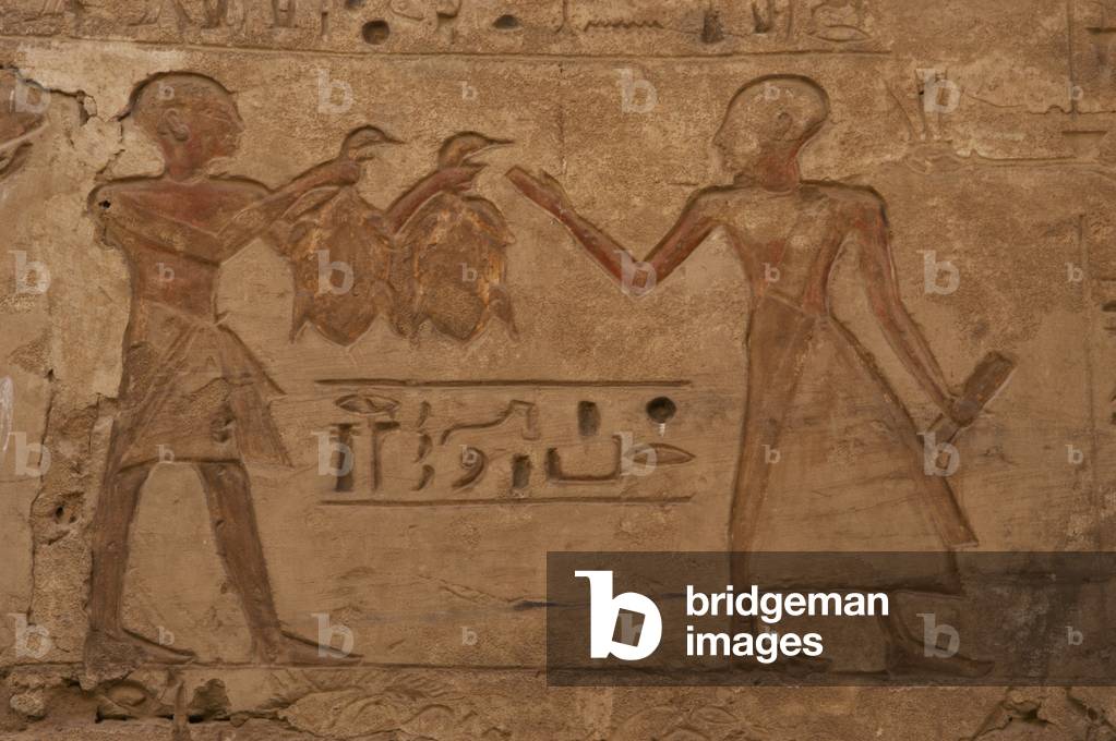 Temple of Ramses III.Two priests with shaved heads. One of them holds two ducks. Egypt.