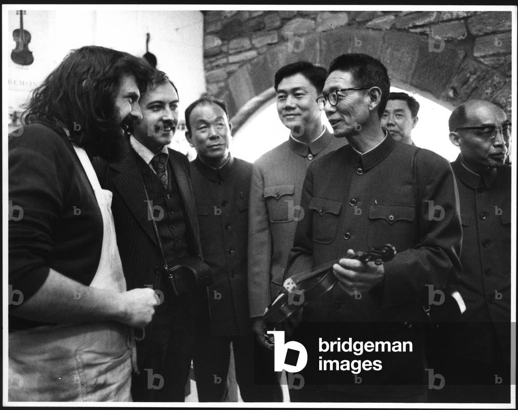 Chinese economic delegation talking to local violin maker Barry Oliver during their visit to Washington, UK, 1970s (b/w photo)