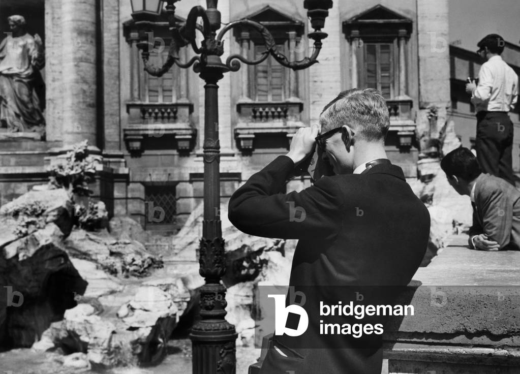 Rome, a tourist photographs the Trevi Fountain, 1960 (b/w photo)