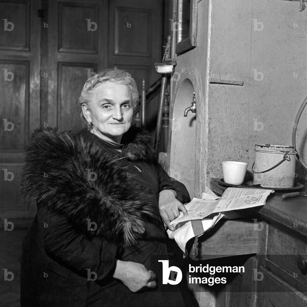 A senior woman keeps herself war with a fur, Germany 1930s (b/w photo)