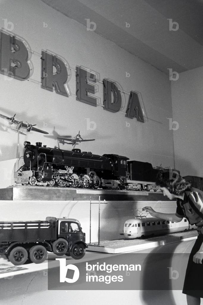 A visitor in front of a stand with models of the italian mechanical engineering corporation Breda on the Leipziger Frühjahrsmesse, Germany 1941 (b/w photo)
