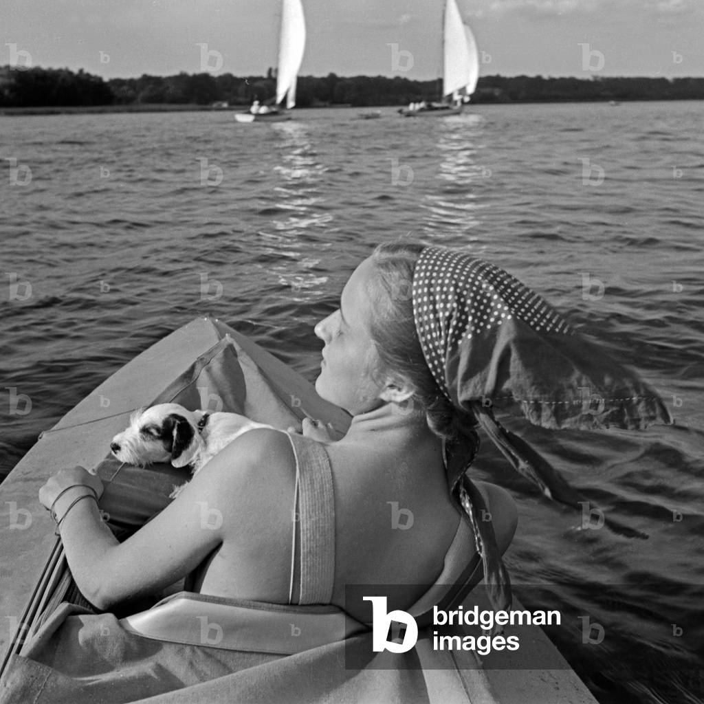Advertising für a Klepper foldboat: a young woman with a puppy paddling on a lake, Germany 1930s (b/w photo)