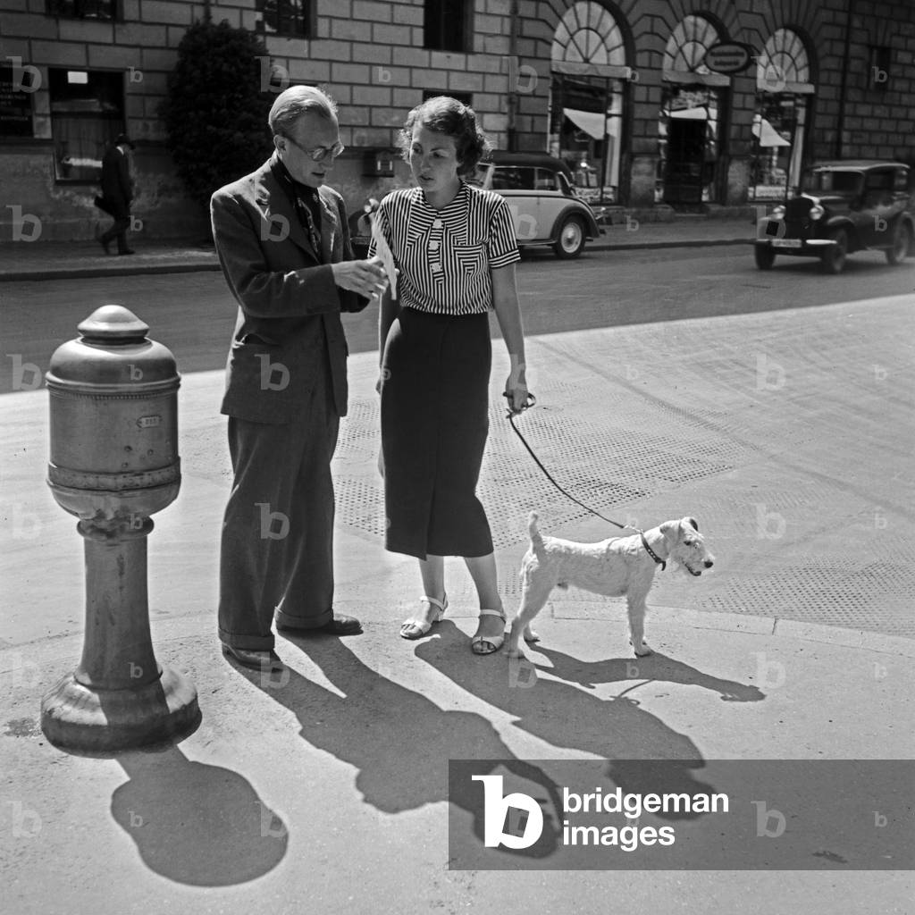 Two walkers with a fox terrier in Munich, Germany 1930s (b/w photo)