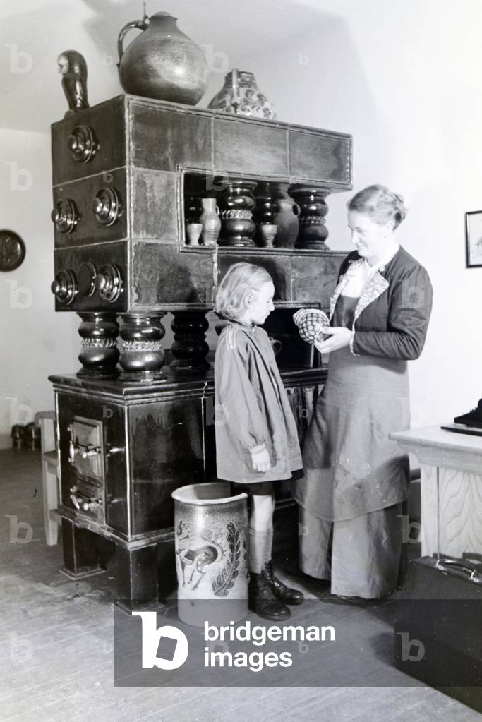 A master potter is showing a finished stoneware jug to a little girl, Germany 1930s (b/w photo)