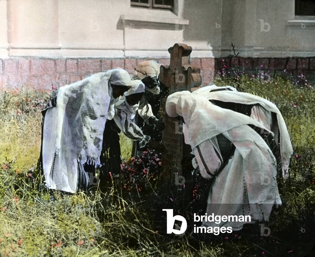 Women taking care of a grave on a graveyard in Romania