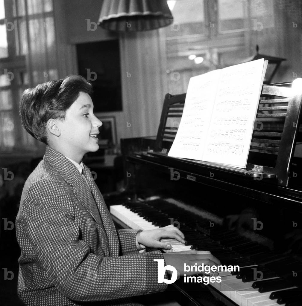 A little boy playing a grand piano