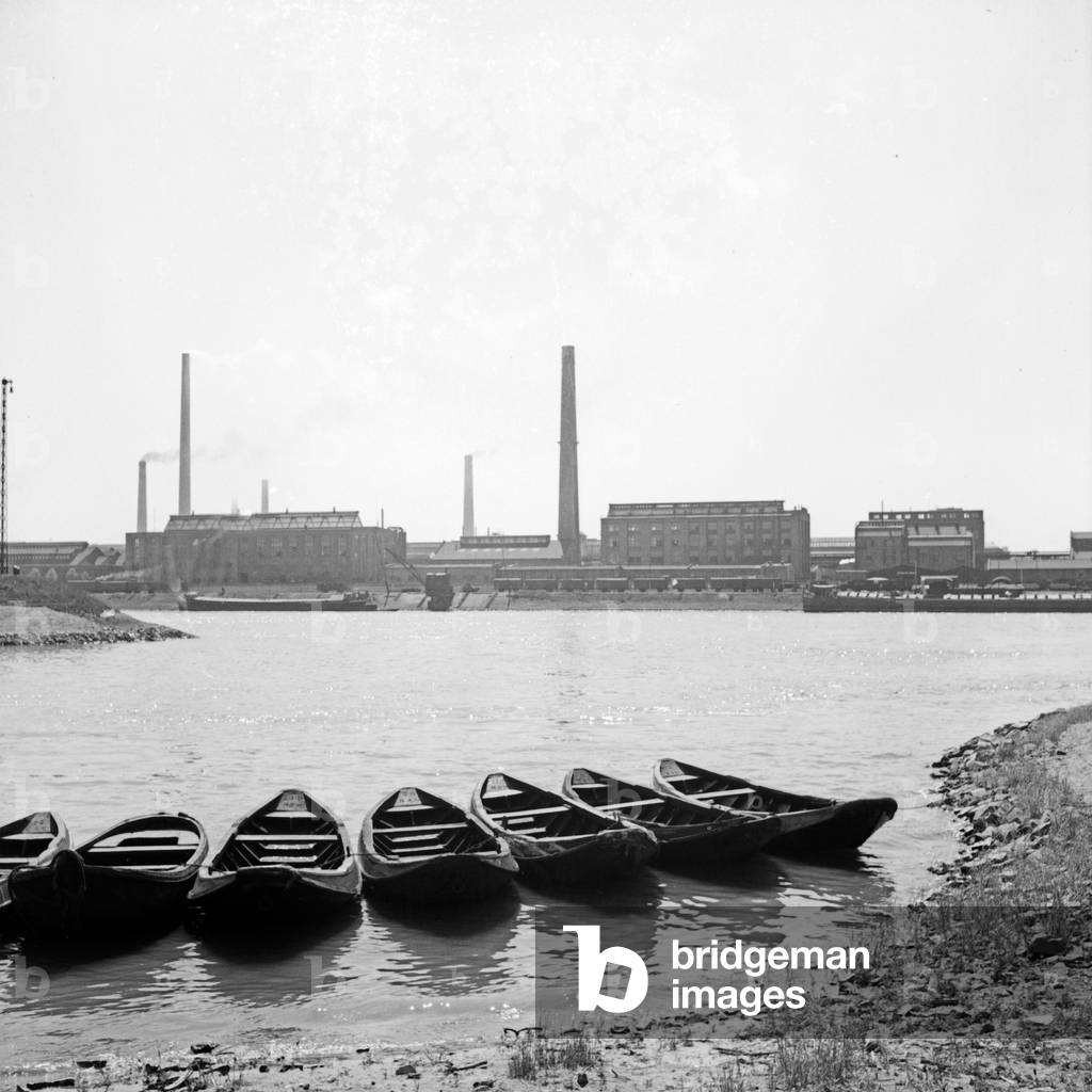 Seven rowing boats at the shore of river Rhine, opposite from the BASF works, Germany 1930s (b/w photo)