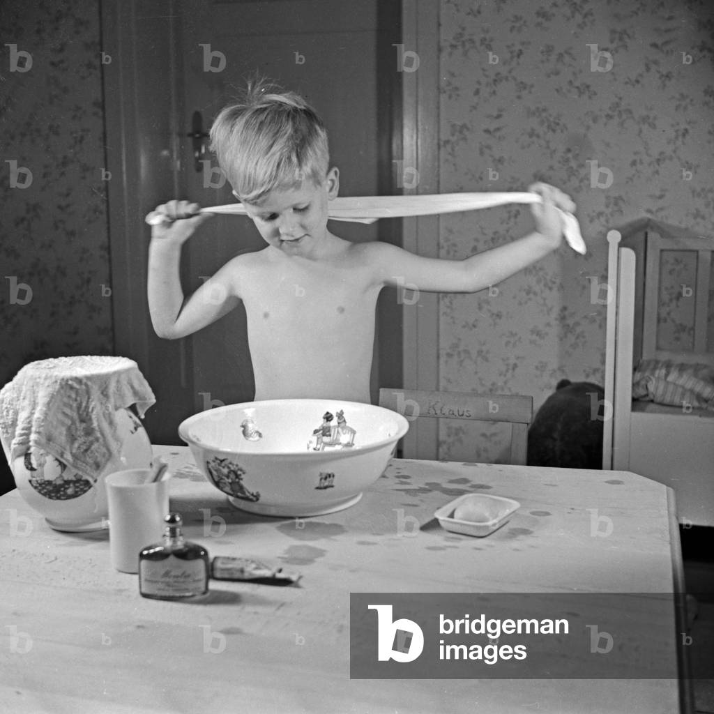 A little boy drying himself with a towel, Germany 1930s (b/w photo)