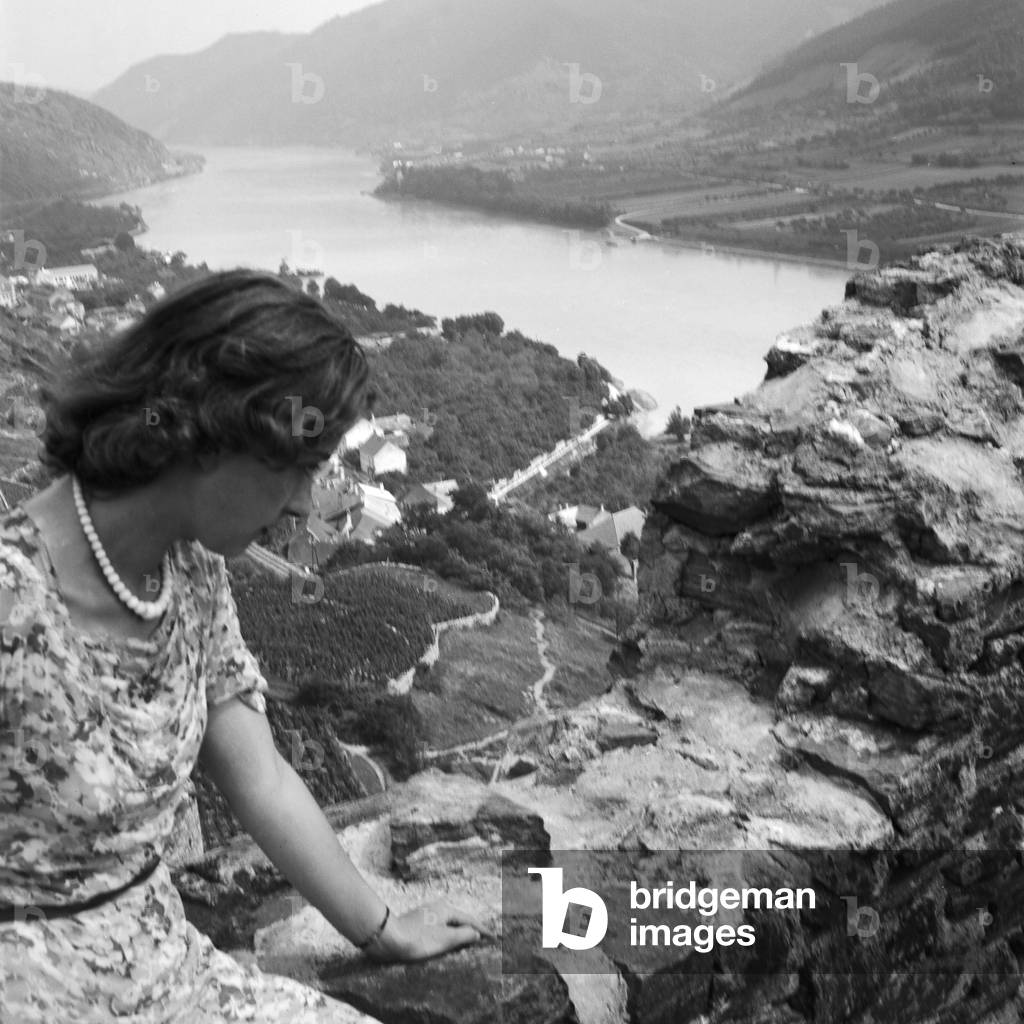 A young woman sitting in the remains of an old castle in the Wachau area in Austria, Germany 1930s (b/w photo)