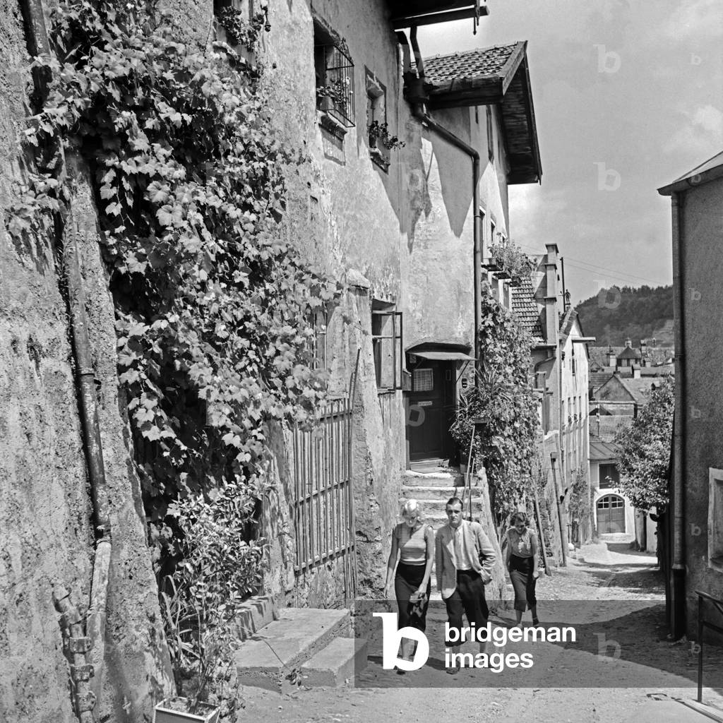 A man and two women strolling through the lanes of Burghausen, Germany 1930s (b/w photo)