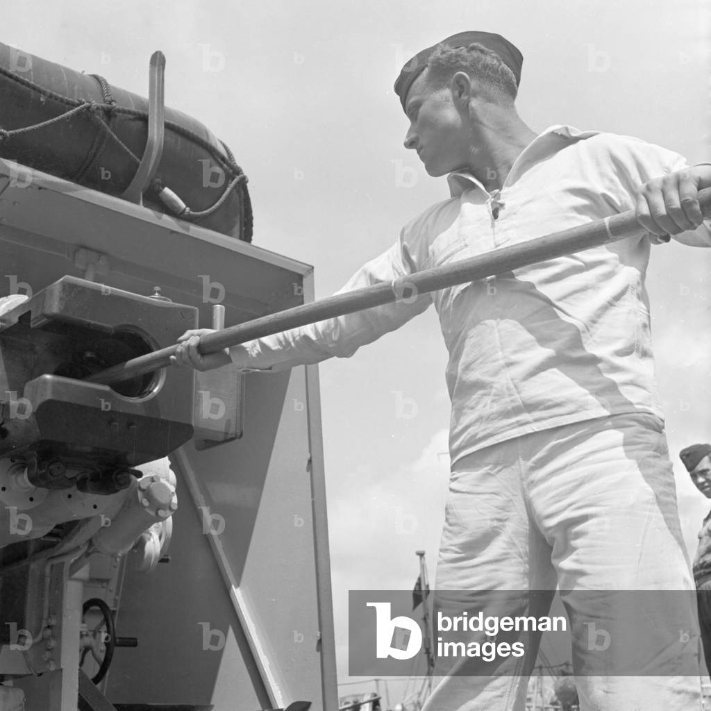 Sailor's duty: cleaning of a cannon of a torpedo boat, Germany 1940s (b/w photo)
