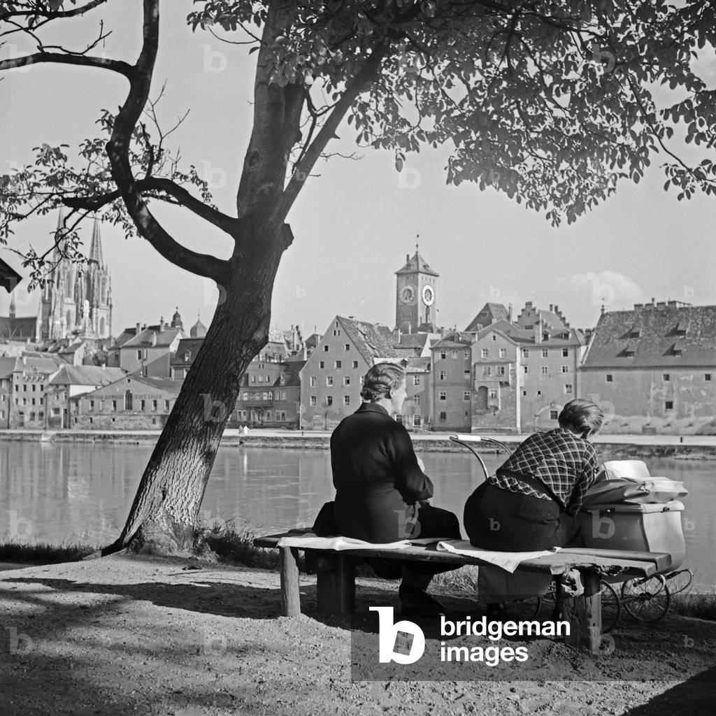 Two women with a pram sitting on the shore of river Danube at Regensburg, Germany 1930s (b/w photo)