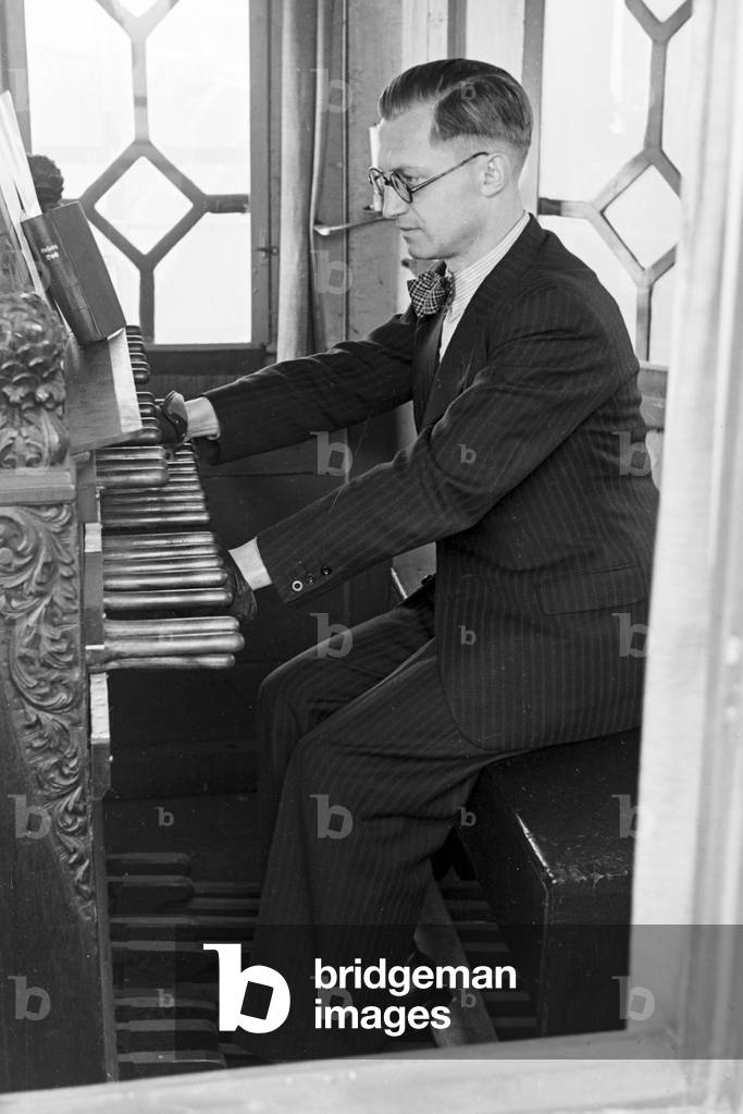 A carillonneur at the carillon keyboard in the Parochialkirche in Berlin, Germany 1930s (b/w photo)