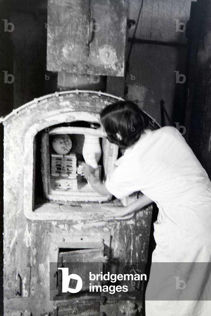 A student of the College for Ceramics is putting newly fictiled vases into the kiln, Höhr-Grenzhausen, Germany 1930s (b/w photo)