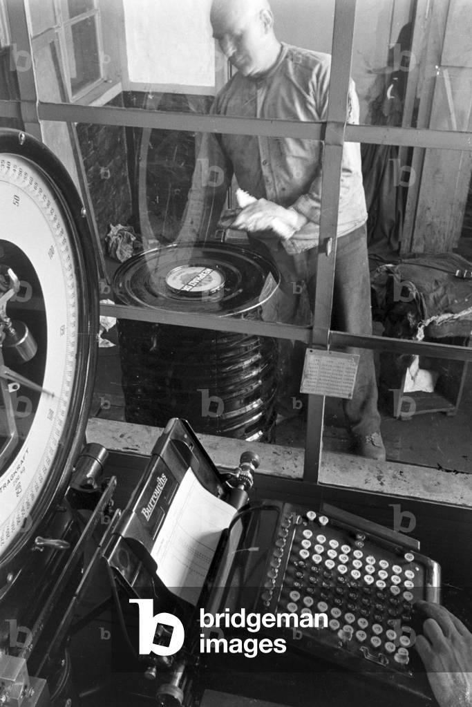 A warehouseman weighing Rhenania Mineraloelwerke AG's product Mexphlat DX at Hamburg, Germany 1930s (b/w photo)