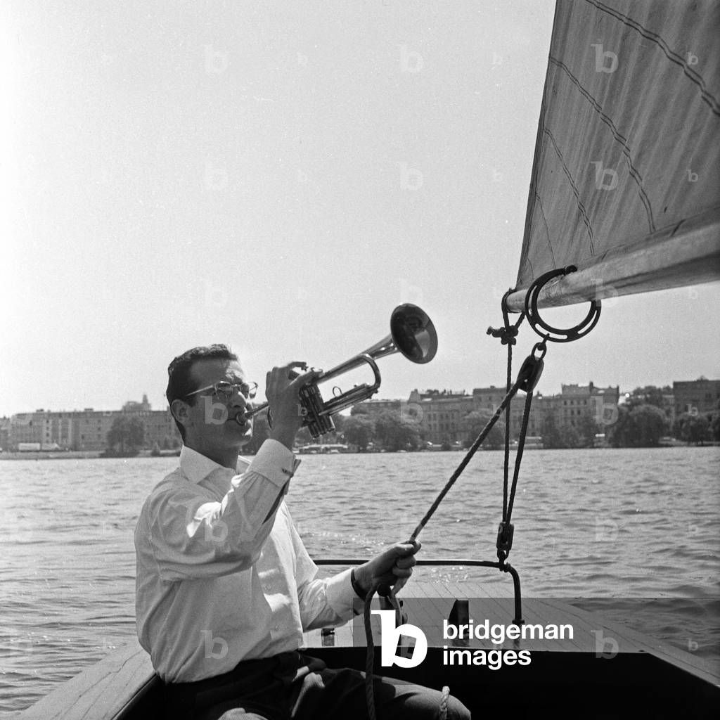 Swiss musician, singer and bandleader Hazy Osterwald sailing and playing his trumpet, Germany 1950s