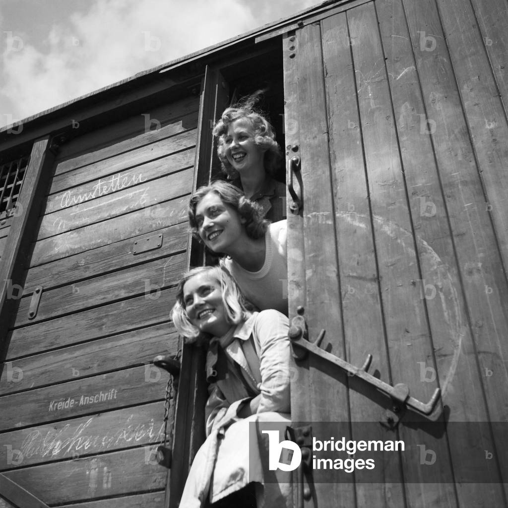 Three young woman in a freight waggon of a train to Amstetten in Austria, Germany 1930s (b/w photo)