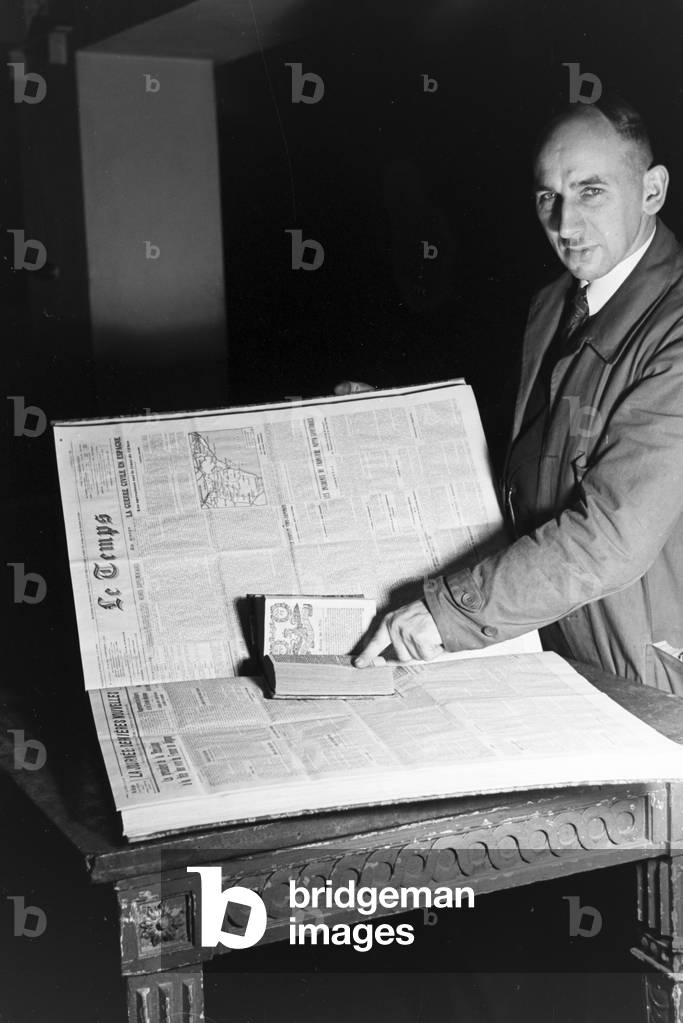 A librarian of the Berlin State Library (former Prussian State Library) presenting an issue of the French newspaper Le Temps, Germany 1930s (b/w photo)