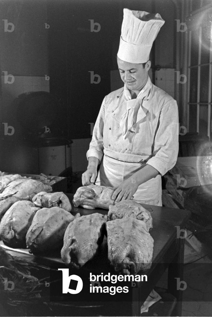 A chef with fresh poultry at the kitchen of a restaurant, Germany 1930s (b/w photo)