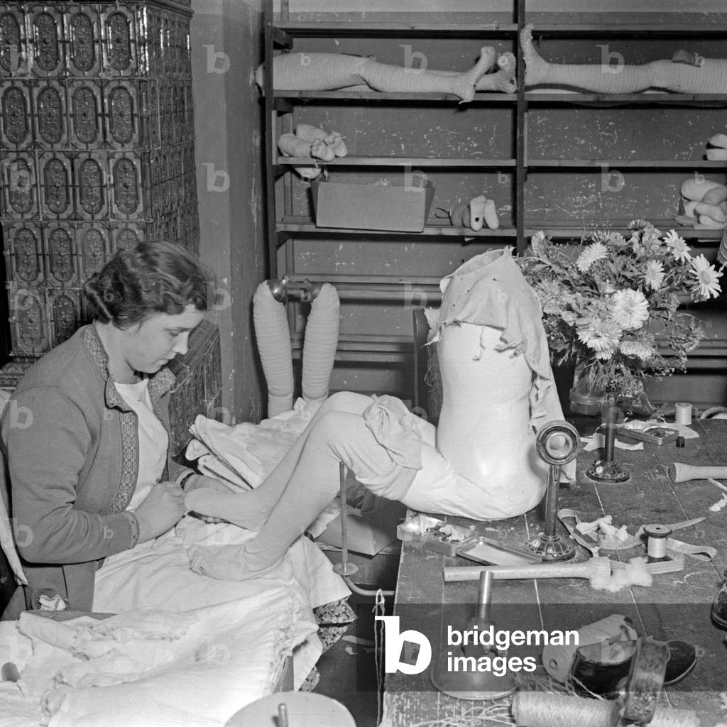 A female staff member creating a Kaethe Kruse display dummy at the factory in Bad Koesen, Germany 1930s (b/w photo)