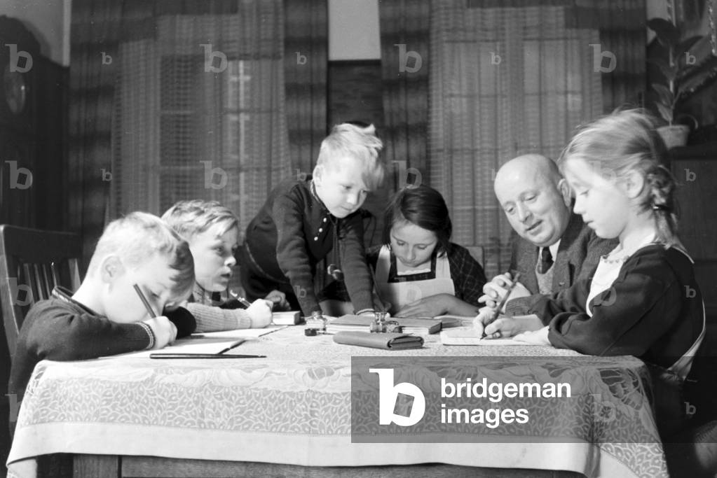 Members of a extended family doing the homework, Germany 1930s (b/w photo)