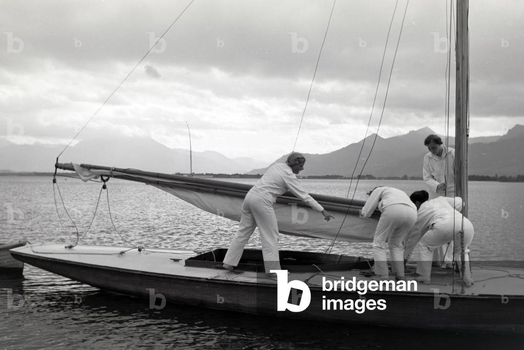 A group of sailors is preparing the canvas on the boat, Chiemsee, Germany 1930s (b/w photo)