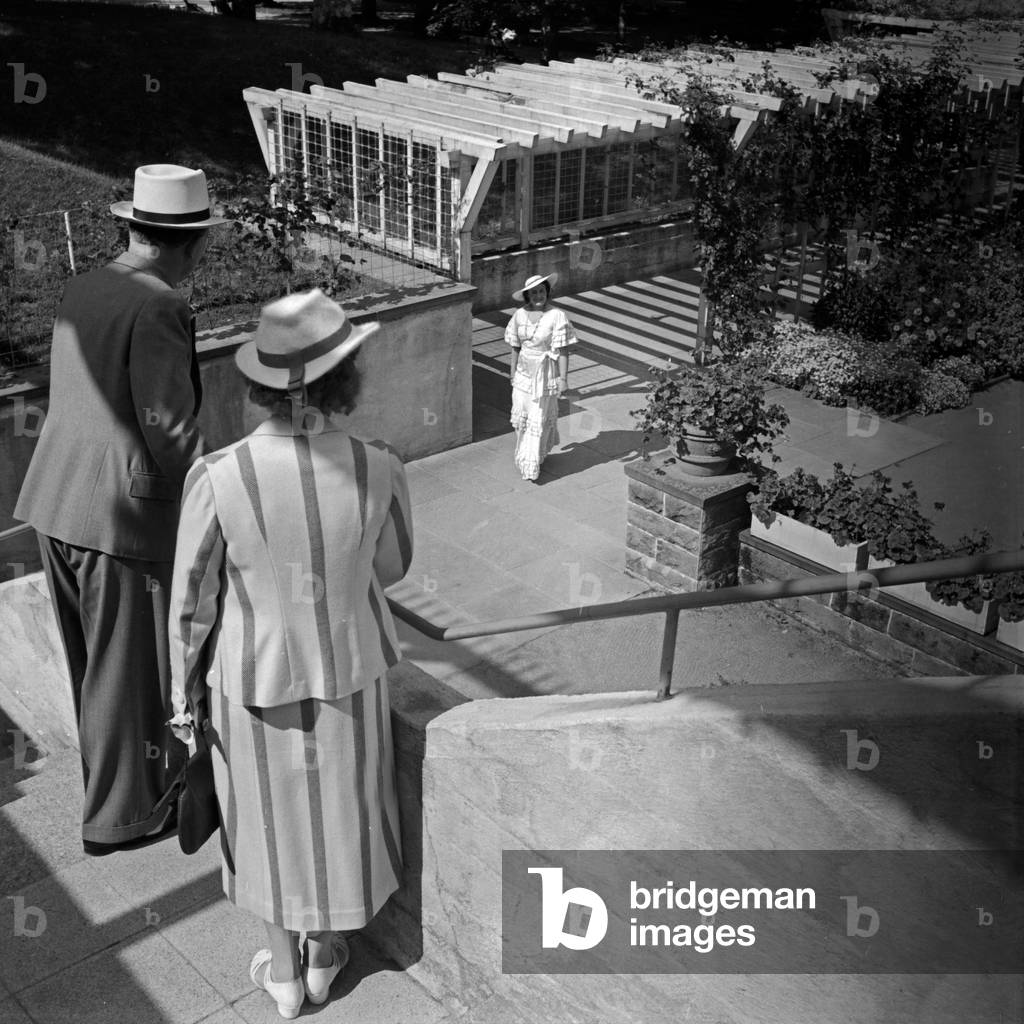 A couple waiting for a woman in a long white dress on a stairs at Wildbad in Black Forest, Germany 1930s (b/w photo)
