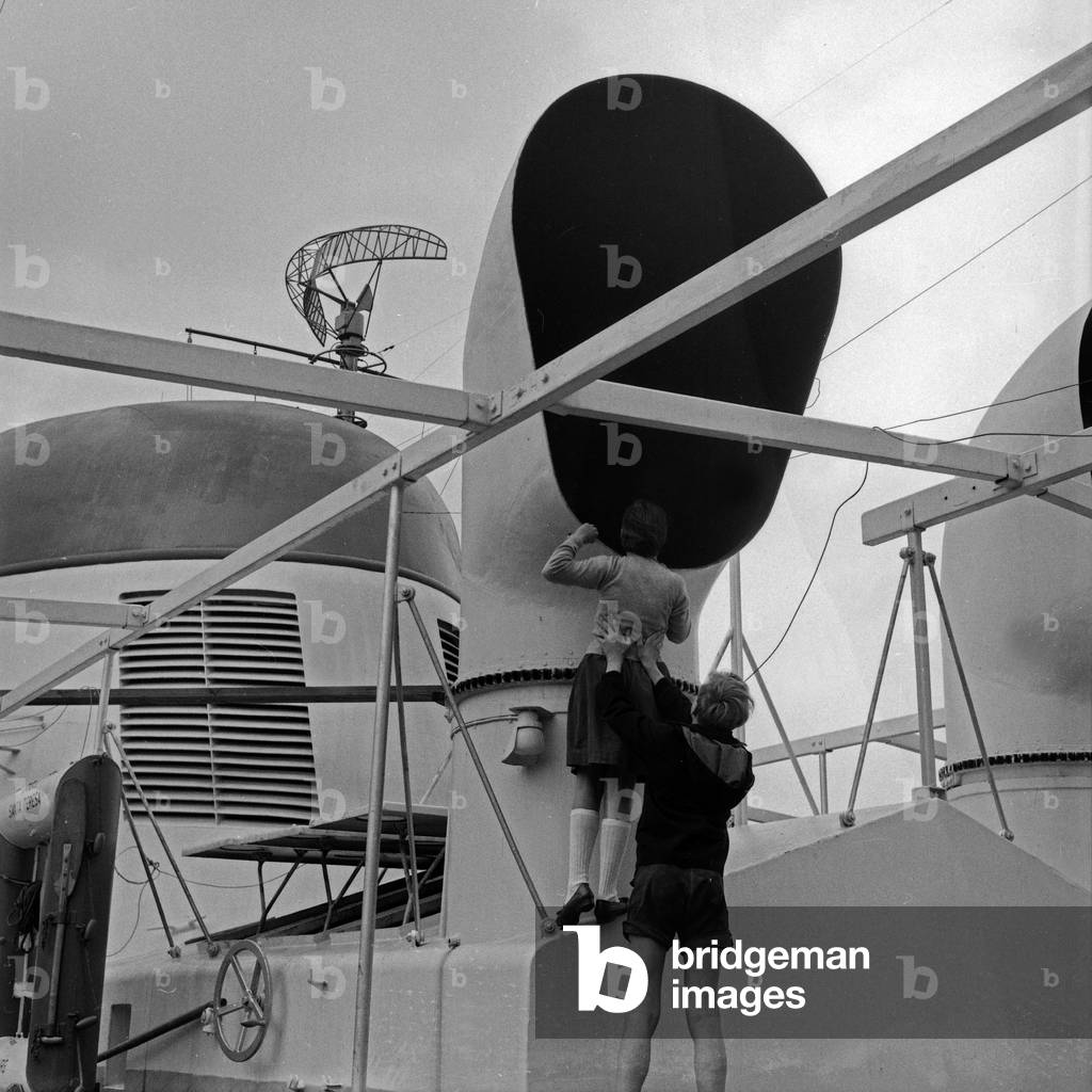 Two children visiting a ship and examing a pipe for air conditioning, Germany 1950s