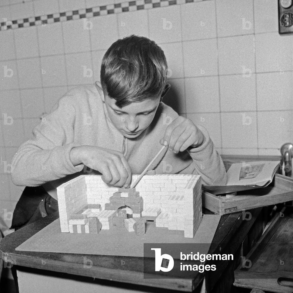 A boy constructing a little house from a model kit, Germany 1950s