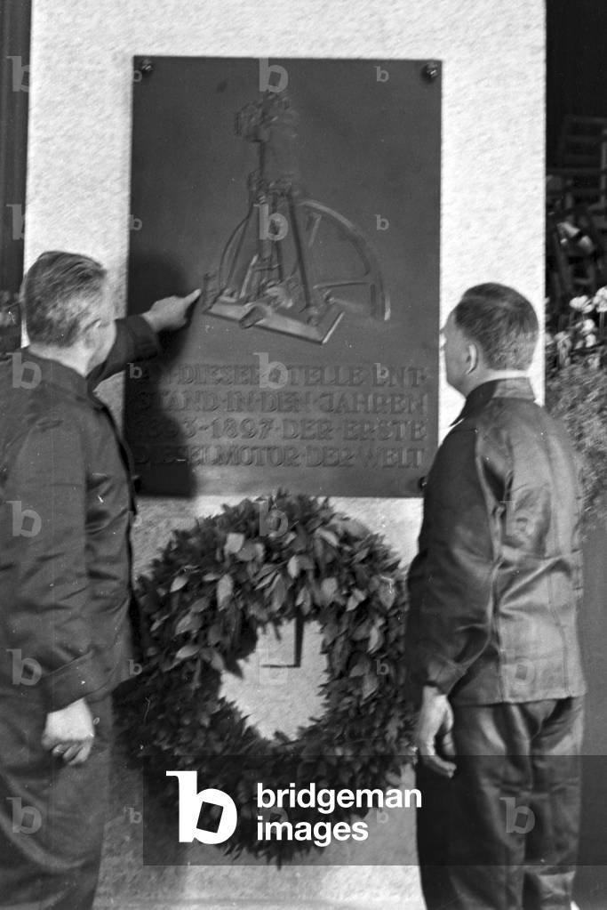 Staff members reading te memorial plate on the Diesel anniversary at the MAN factory at Augsburg, Germany 1930s (b/w photo)