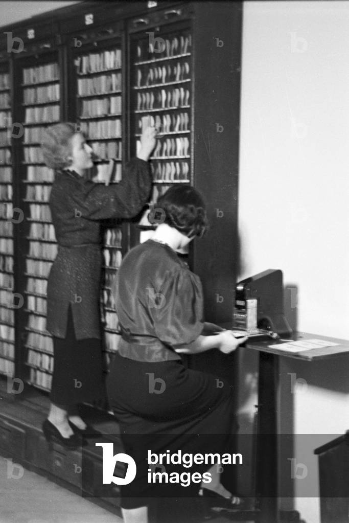 Travellers and staff members at a huge office of a travel agency in Berlin, Germany 1930s (b/w photo)