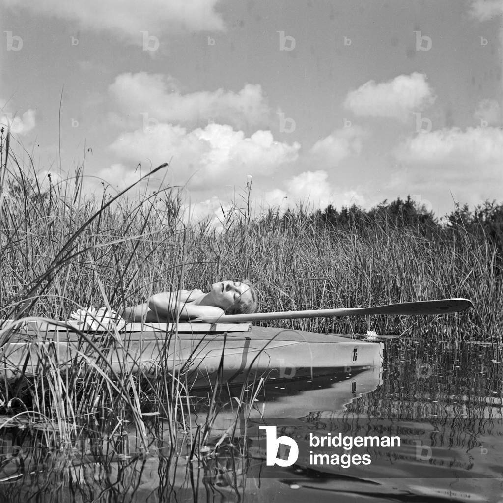 A young woman with her folding boat in the reed of a lake in the Wachau area, Germany 1930s (b/w photo)